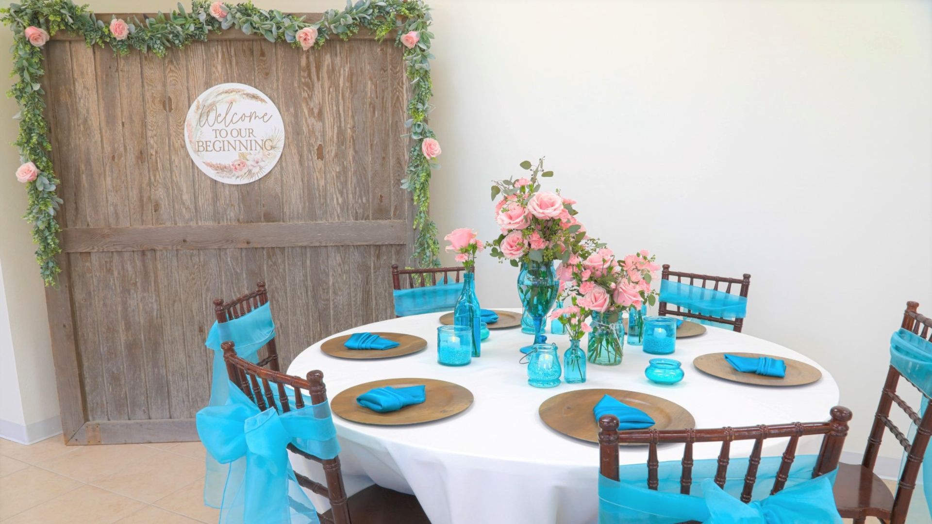 cream and blue wedding tablescape with wooden backdrop and pink roses